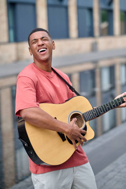 istock Man playing guitar with inspiration standing on street 1364634745