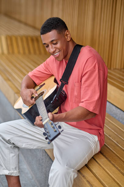 istock Cheerful man playing guitar sitting outdoors 1364634747
