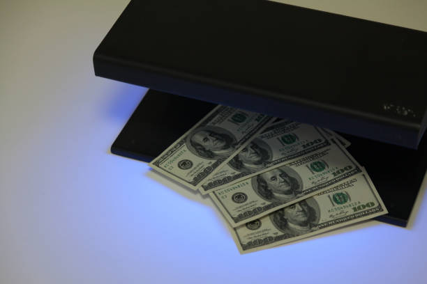 istock Dollar bills lie inside black metal detector 1364636196