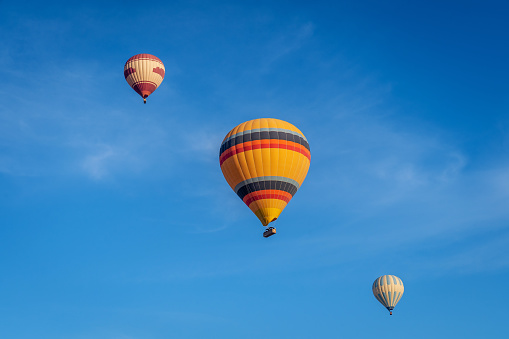 Isolated multicolor hot air balloon flying in a blue sky with white clouds at the Albuquerque International Balloon Fiesta.