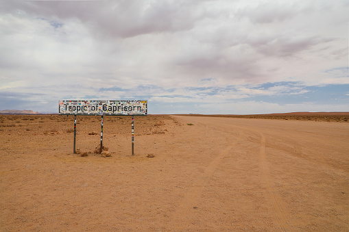 Tropic of Capricorn sign covered in stickers in the Namib desert along the roadside