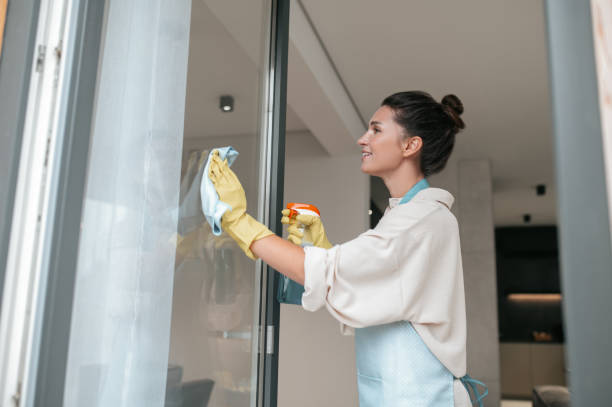 istock A woman in apron cleaning the windows and looking involved 1364638530