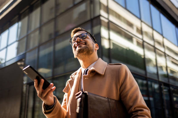 Young businessman using phone on his way to work stock photo