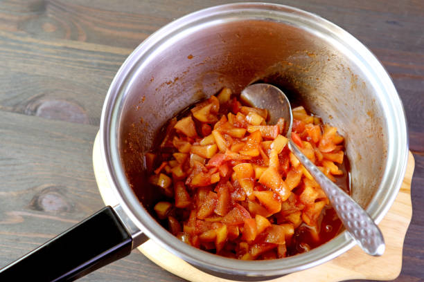 Pot of fresh cooked caramelized homemade apple compote on wooden table Pot of fresh cooked caramelized homemade apple compote on wooden table apple compote stock pictures, royalty-free photos & images