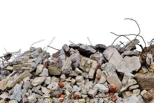 Construction waste in the form of a pile of concrete fragments, bricks and protruding rebar isolated on a white background.