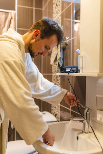 istock Young man wearing a bathrobe brushing his teeth in the bathroom after taking a shower 1364642554