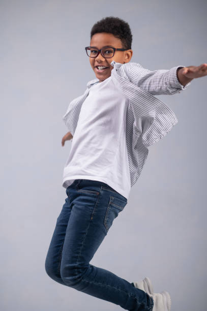 istock Happy dark-haired bespectacled young boy jumping up 1364643358