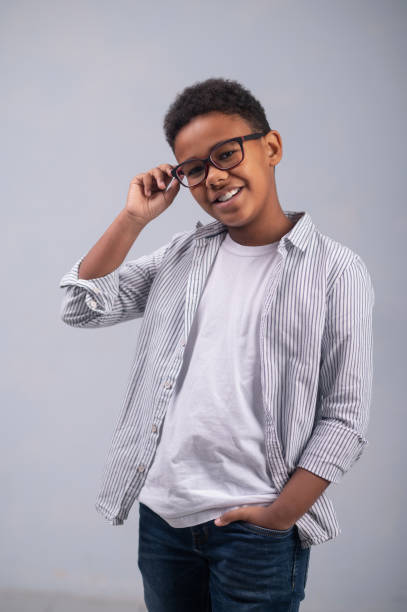 Cheerful young boy in trendy eyeglasses looking before him stock photo