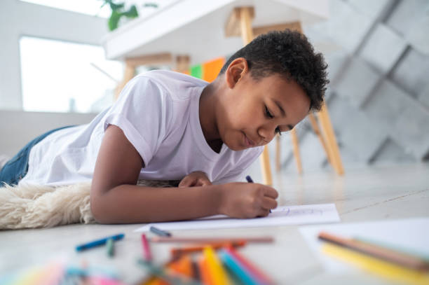 istock Boy lying on stomach on floor drawing with pencil 1364643459