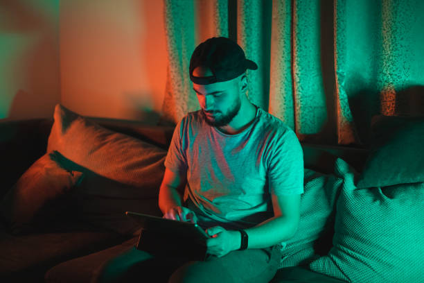 istock Young bearded happy man using his tablet with RGB lights in the background while casually working from home 1364643733