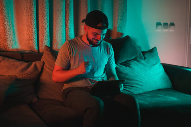 istock Young bearded happy man using his tablet with RGB lights in the background while casually working from home 1364643852