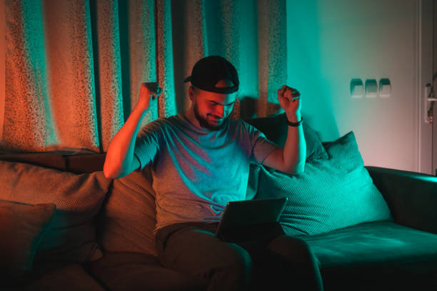 istock Young bearded happy man using his tablet with RGB lights in the background while casually working from home 1364643857