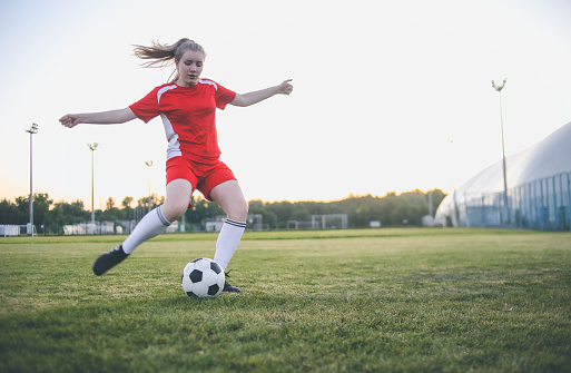 Close up of female soccer player kicking the ball at the goal