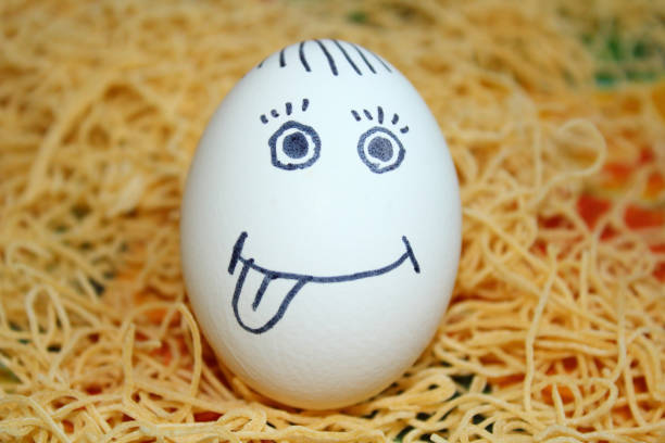 Chicken egg with painted face standing on homemade noodles. Close-up.