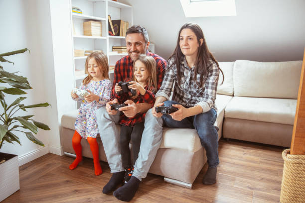 istock Family with two young daughters having fun while playing video games 1364646336