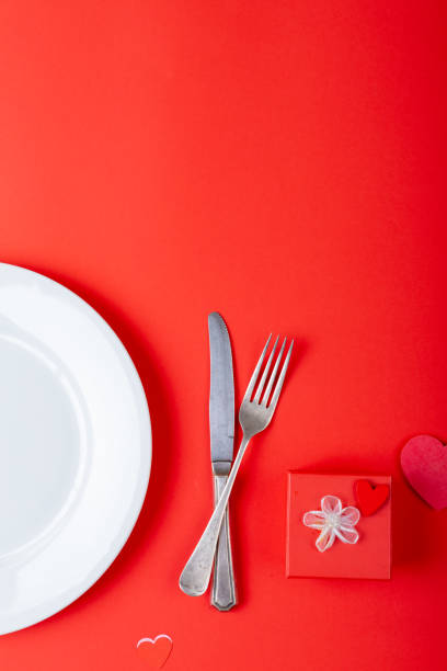 istock Overhead view of place setting by valentine gift on red background, copy space 1364647440