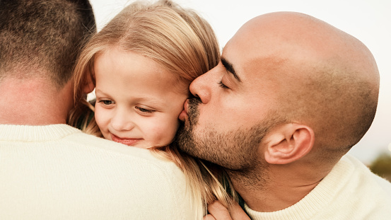 Gay male fathers kissing kid son outdoor - LGBT family having fun - Love concept