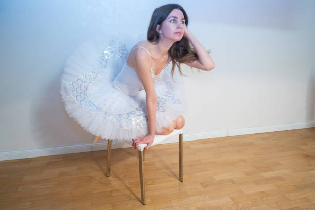 Ballerina in a white tutu sits on a bedside table