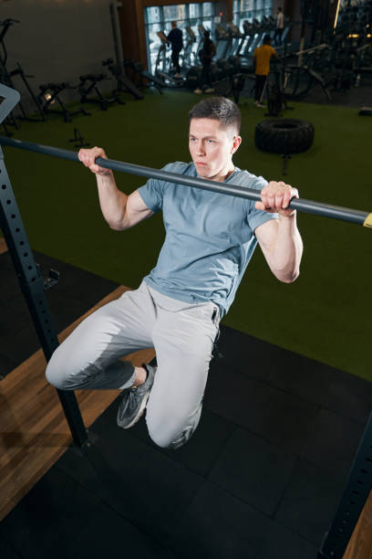 istock Concentrated male athlete performing pull-ups at gym 1364650286