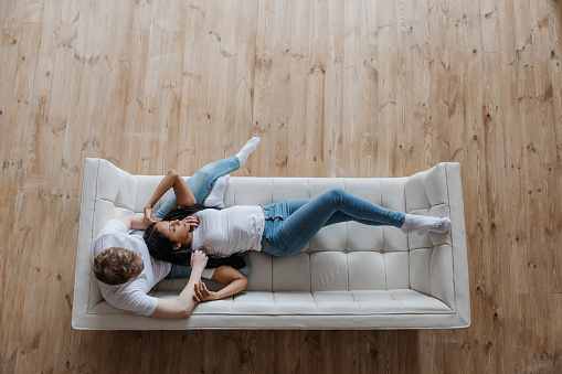 View from above affectionate young multiracial couple cuddling on sofa. High quality photo