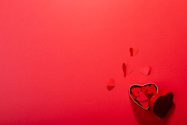 istock Overhead view of heart shaped decoration and gift box on red background, copy space 1364651494