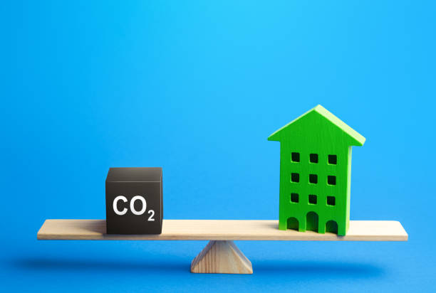住宅用建物とco2排出量をスケールで削減。温室効果ガス排出量。エネルギー効率を向上させ、環境への影響を低減脱炭素化。気候変動。年間公害計算 - 脱炭素 ストックフォトと画像
