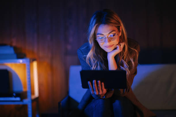 retrato de uma linda mulher com óculos sentados e usando seu tablet à noite - glasses women smiling human face - fotografias e filmes do acervo