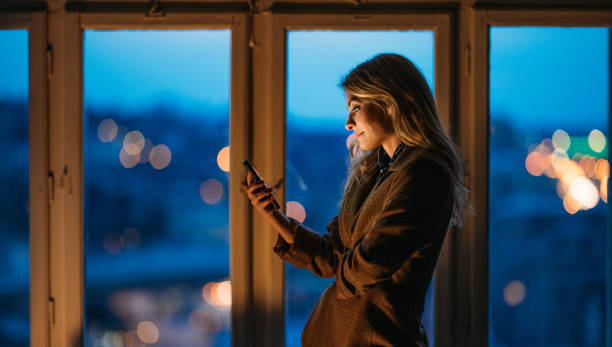 istock Beautiful Entrepreneur Using her Mobile Phone in the Evening at the Office 1364657842