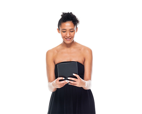 Waist up of aged 20-29 years old who is beautiful african-american ethnicity young women standing in front of white background wearing dress who is happy and using digital tablet