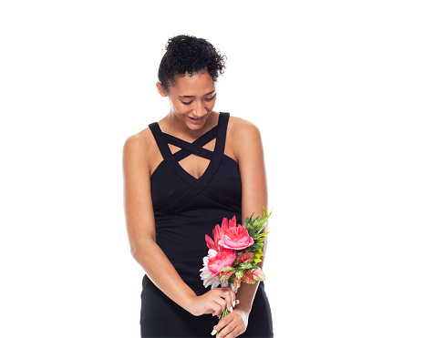 Full length of aged 20-29 years old who is beautiful african-american ethnicity young women in front of white background wearing dress who is cheerful and holding flower