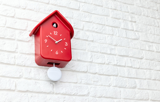 Red cockoo clock on white brick wall