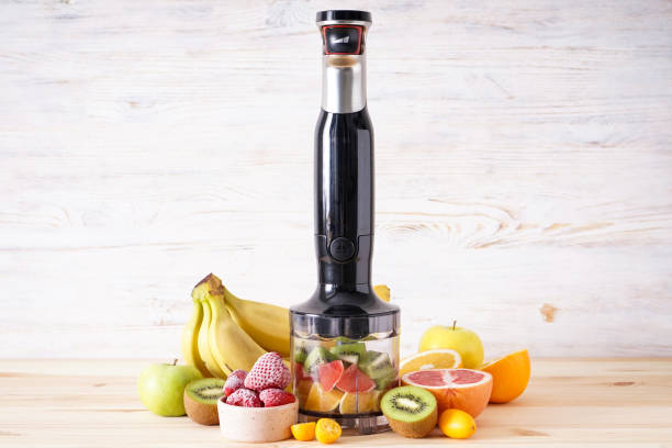 istock Black plastic electrical hand blender and accessories with sliced fruit on a wooden background. 1364669502