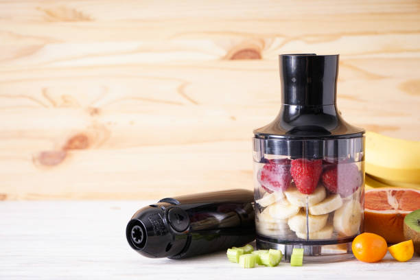 istock Black plastic electrical hand blender and accessories with sliced fruit on a wooden background, place for text. 1364669553