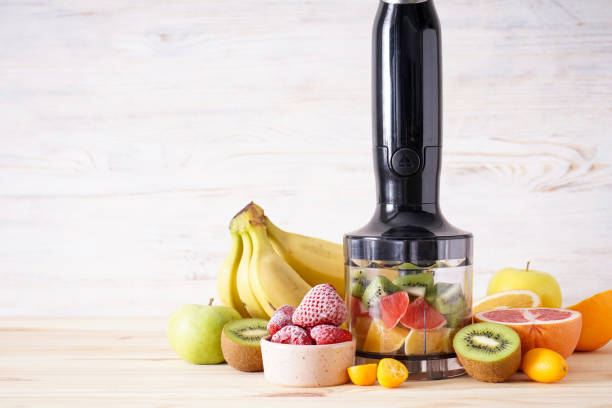 istock Hand blender and accessories with sliced fruit on a wooden background, place for text. Close up. 1364669601