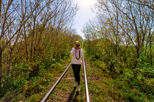 Woman taking a picture with reflex camera on railway tracks