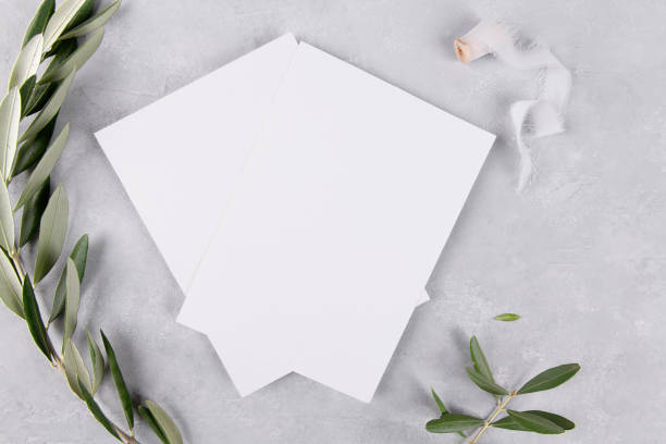 istock Two blank wedding invitation stationery card mockup on grey stone table background with olive branches, 5x7 1364677557