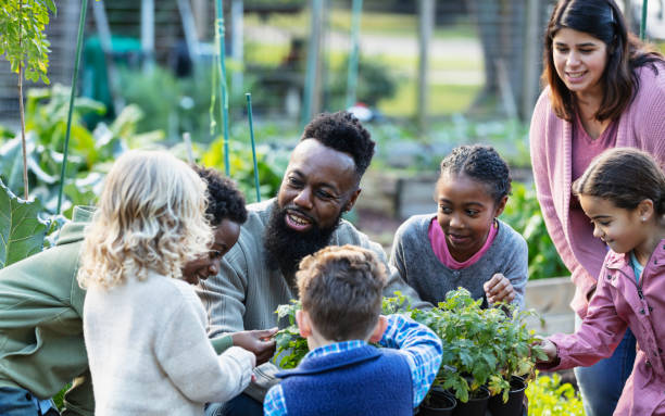 コミュニティガーデンで植物について子供たちに教える男 - teaching field trip classroom child ストックフォトと画像