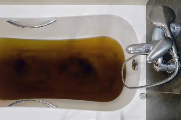 Photo of A bathtub filled with dirty water due to a clogged sewer pipe, close-up