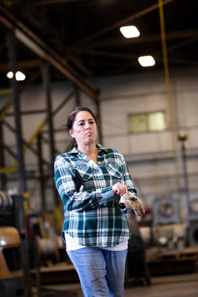 istock Woman walking in warehouse putting on work gloves 1364681973