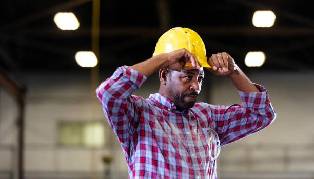 istock African-American man in warehouse putting on hardhat 1364682246