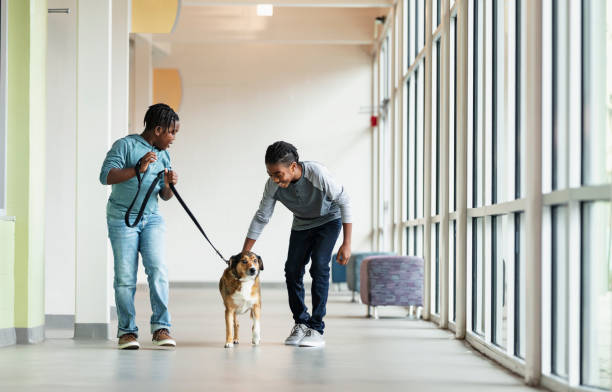 African-American boys walking dog in pet shelter hallway