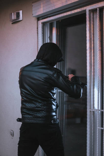 istock Burglar with torch trying to open the window with crowbar tool 1364683886
