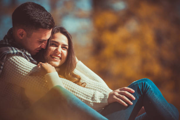 istock Romantic couple hugging and sitting in the park 1364685538