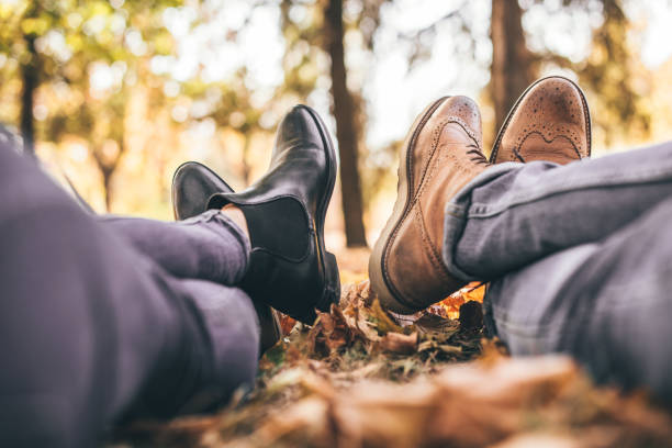 Cute couple is resting in the park and showing their boots