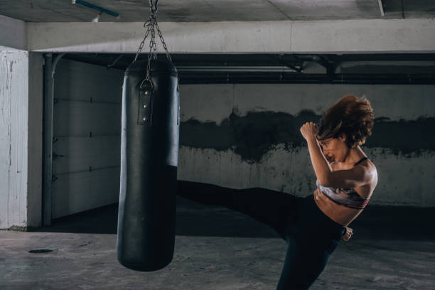 istock Young sportswoman doing high kick during boxing exercise in a garage. 1364686855