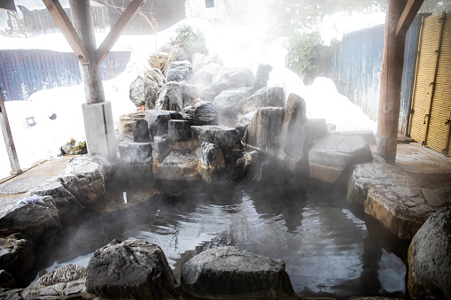 Japan is famous for hot spring baths. An outdoor hot spring bath with rock waterfall and snow around usually found at a Japanese Inn or Ryokan.