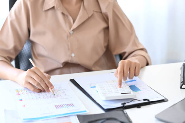 istock Cropped shot businesswoman writing information on document and using calculator. 1364715038