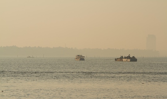A boat towing a barge in the lake during Sunrise