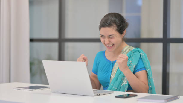 istock Indian Woman Celebrating Success while using Laptop in Office 1364718439