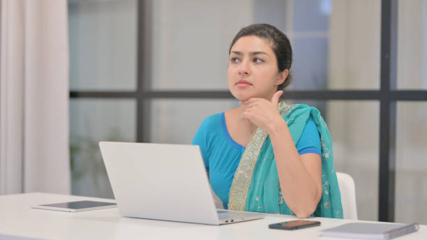 istock Indian Woman Thinking while Working on Laptop in Office 1364719066